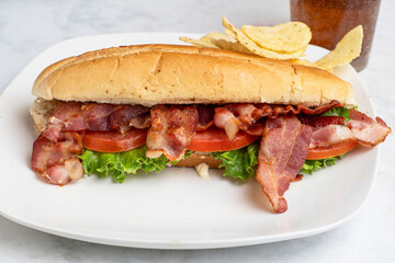 blt sub  served with a soft drink and chips