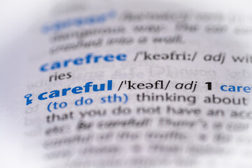 Careful word in a dictionary. Selective focus, close up.