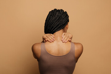 African american woman in white top massaging her neck, got muscle cramp strain in the end of...