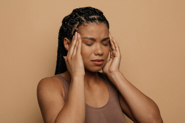 Closeup studio shot of unhappy pretty young african woman suffering from headache, touching...