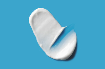A sample of white cosmetic moisturizer on a blue background