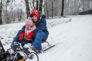 Sledding fun on a snowy winter day with kids in a forest setting