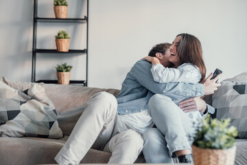 Excited millennial husband and wife relax on couch in kitchen feel euphoric win lottery online on...