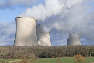 View of a nuclear power plant with its cooling towers and fields in the foreground.