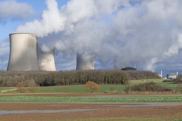 View of a nuclear power plant with its cooling towers and fields in the foreground.