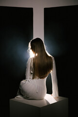 Portrait of a woman in a studio with professional lighting in a white long dress, soft focus