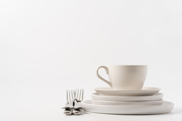 Clean white dishes on white background with copy space. Cleaning, washing dishes concept background