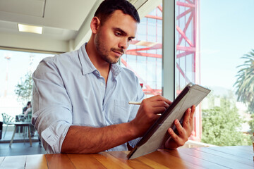 Businessman using stylus pen while working on digital tablet in modern office