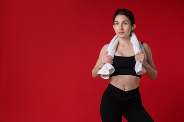 Woman in sportswear with towel on red background, space for text