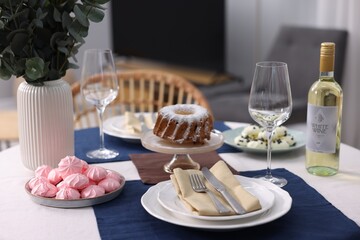Festive table setting with dishware, desserts, wine and glasses indoors