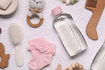 Baby oil, socks and accessories on white towel, top view