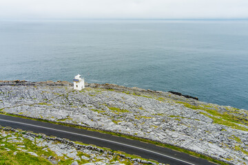Black Head Lighthouse, situated in the rough rocky landscape of Burren, amidst a bizarre scenery of...