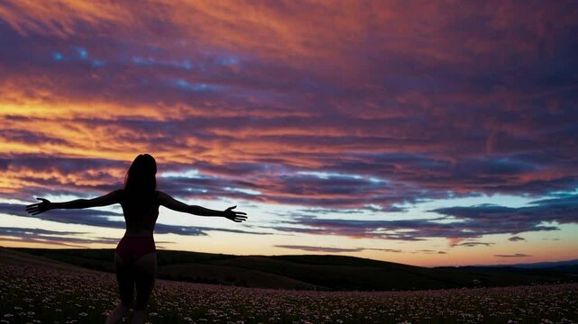 Happy woman standing with her back on sunset in nature with open hands.