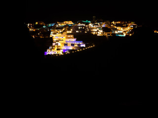 Lights of night illumination of cascading houses and hotels on the hills of Santorini, Greece. Night landscape