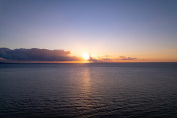 Start of a new day with the sun coming through a long cloud reflecting its light on the Mediterranean sea at the Sun Coast. Aerial seascape with colourful early morning weather conditions