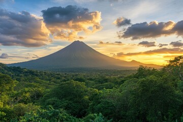 Fototapeta premium Majestic View of a Volcano Surrounded by Lush Green Forest under a Stunning Sunset Sky with Fiery Clouds Creating a Breathtaking Natural Landscape