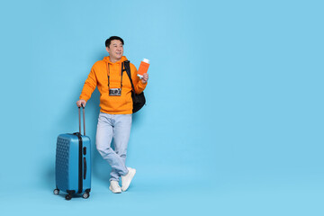 Happy traveller with passport, suitcase and camera on light blue background. Space for text