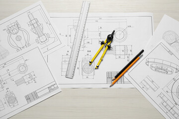 Different engineering drawings, pencils, ruler and divider on wooden table, flat lay