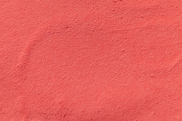 Fototapeta premium The image shows a close-up of a smooth, coral-colored surface with a subtle texture. Its uniformity and fine grains create a calming, simple aesthetic. Macro shot of a used blush palette
