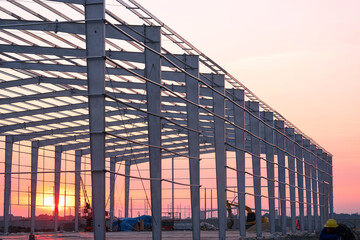 Factory building framework structure with worker working overtime in construction site against...