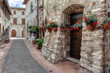 Charming cobblestone street in medieval Assisi, Umbria, Italy featuring rustic stone buildings and vibrant flower pots