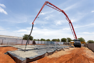 concrete boom pump arm pouring concrete foundation at construction site, reinforced foundation with steel rebar, cover concrete with plastic foil