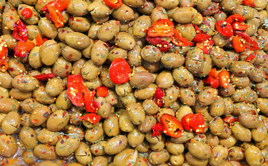 background of large green olives in brine and with red hot peppers