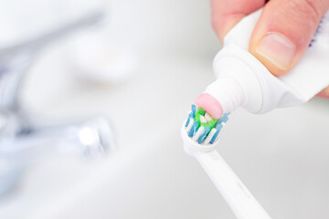 Preparing toothpaste on electric toothbrush in the morning