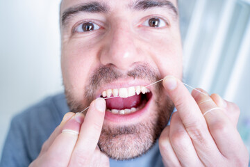 Man and oral hygiene routine using dental floss
