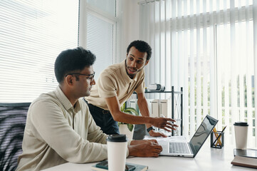 Business partners discussing online project on laptop in team in office