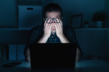 Man with eye strain computer problem at night