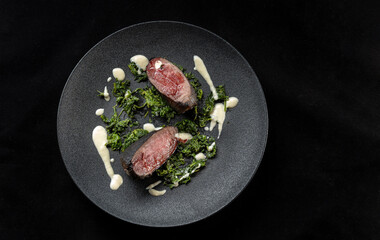 This gourmet dish features grilled meat on fresh spinach with a rich, flavorful sauce. Top view