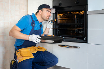 One repairman fixing malfunctioning kitchen oven problem