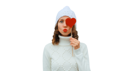 Winter christmas portrait of beautiful happy young woman blowing kiss with lollipop in white hat