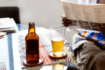 Black, elegant senior man using african clothes, drinking brazilian  beer and listening samba, Brazilian traditional music in to vinyl player in his Brazilian home. African man.