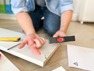 One man hitting his thumb with the hammer assembling furniture part