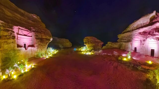 Illuminated Nabataean tombs carved into sandstone cliffs at night in Hegra archaeological site Al-Ula, Saudi Arabia. Highlighting ancient architecture and cultural heritage in Madain Saleh necropolis.
