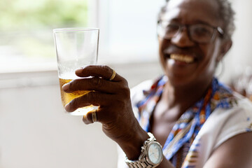 Black, elegant senior man using african clothes, drinking brazilian  beer and listening samba,...