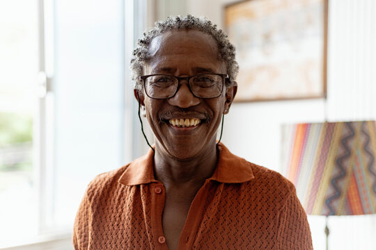 Black elegant senior man, drinking brazilian  beer and listening samba, Brazilian traditional music in to vinyl player in his Brazilian home. African man.