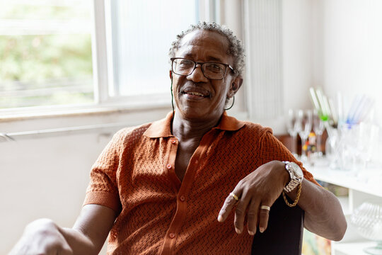Black elegant senior man, drinking brazilian  beer and listening samba, Brazilian traditional music in to vinyl player in his Brazilian home. African man.