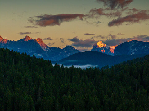 Scenic aerial morning view of misty valleys and forested landscapes in the Dolomites, with Antelao and Cridola peaks in the background. Captured near Danta village, Italy. Hiking in Dolomites.