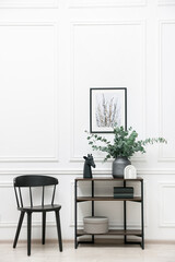 Console table with decor and chair near white wall in room. Interior design