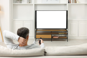 Man watching TV on sofa at home, back view