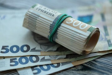 Many five hundred hryvnia money bills lies on wooden background. Ukrainian national currency close...
