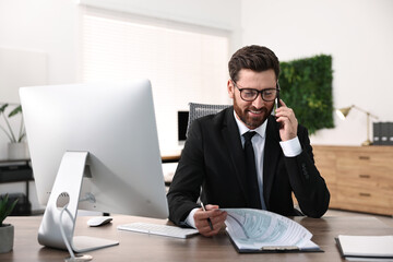 Man talking on smartphone while working at table in office