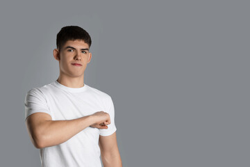 Man making promise on grey background, space for text. Oath gesture