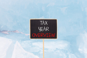 Tax year overview symbol. Concept words Tax year overview on beautiful black yellow blackboard. Beautiful blue Baikal ice background. Business tax year overview concept. Copy space.