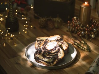 Cozonac sits elegantly on a rustic platter, inviting with its swirls of chocolate and sweet aroma....