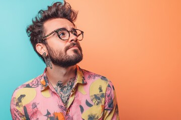 Fototapeta premium Stylish Young Man with Tattoos and Glasses Against a Colorful Background