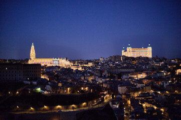 The historic center of Toledo illuminated at night, showcasing its medieval charm and architectural beauty under the night sky in Castilla la Mancha, Spain